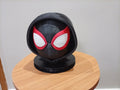 Cabeça decorativa de Miles Morales com capuz preto e base redonda, vista frontal