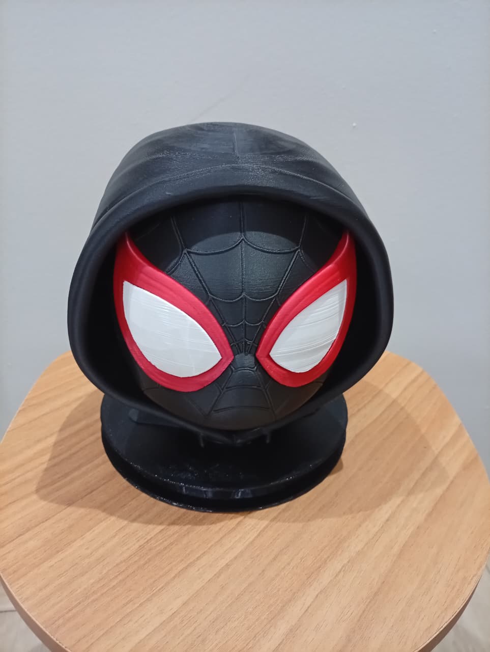 Cabeça de Miles Morales com capuz sobre base redonda